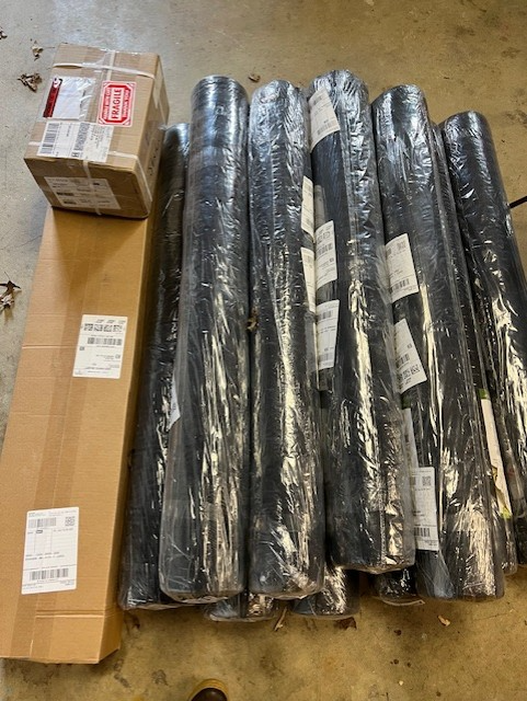 Several rolls of black landscape fabric encased in plastic. 